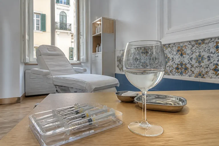 Siringhe con filler acido ialuronico e bicchiere su tavolo in ambulatorio medico elegante